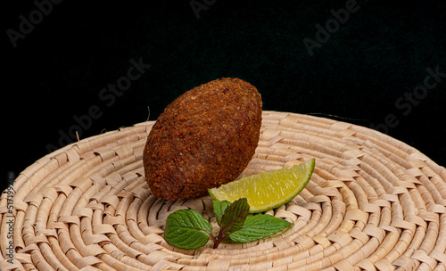 Fried kibbeh on straw mat with mint and lemon photo