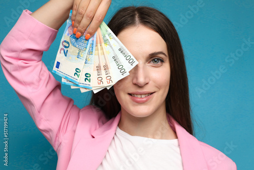 young woman holding euro bills near her face