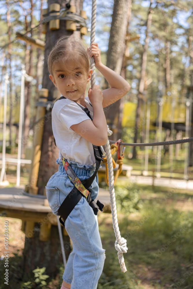 Kid climbing in high rope course in adventure park. Children in forest rope park.Summer camp for kids. Kid climbing in high rope course in adventure park. Children in forest rope park.Summer camp for kids.