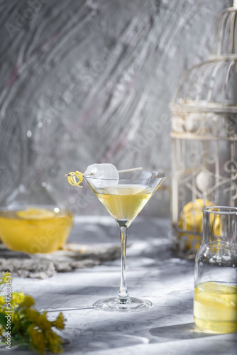 Selective focus lemon lemonade with ice in martini glass with lemon zest garnish  