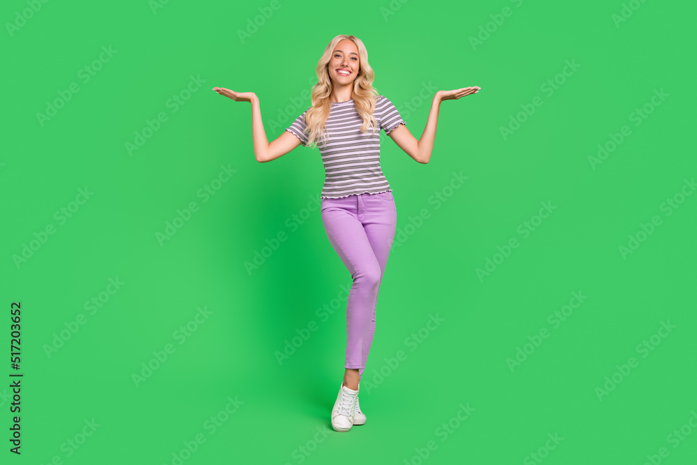 Full body portrait of cheerful positive person arms palms demonstrate empty space isolated on green color background Full body portrait of cheerful positive person arms palms demonstrate empty space isolated on green color background