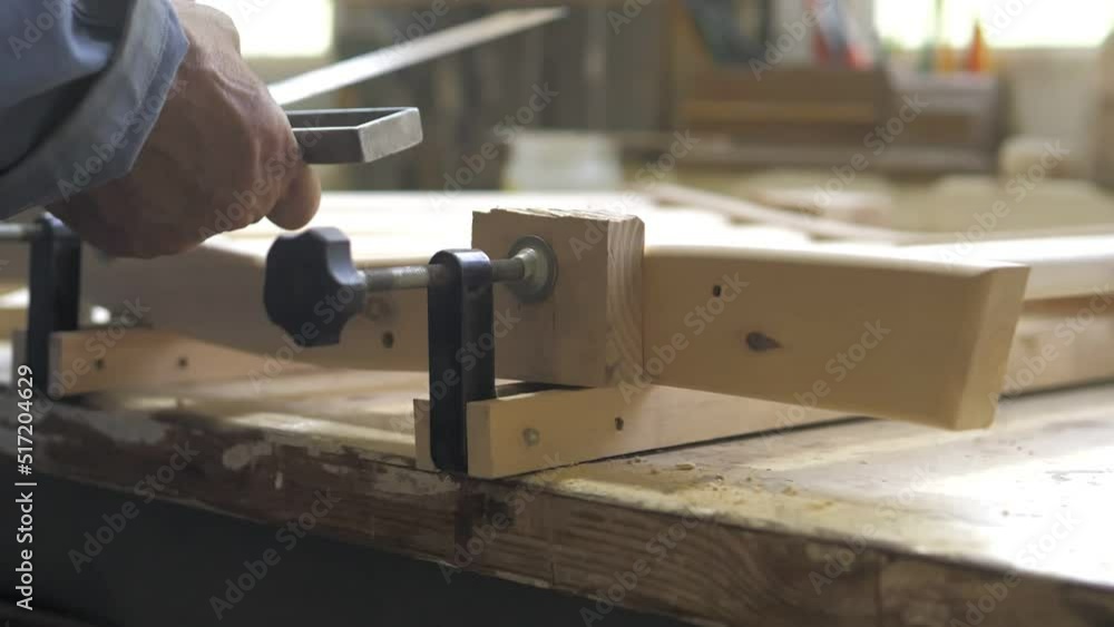 Slow motion. Close-up of a carpenter tightening two screw clamps to a piece of light wood. A professional carpenter collects wooden furniture parts in a carpentry workshop.Handmade furniture Slow motion. Close-up of a carpenter tightening two screw clamps to a piece of light wood. A professional carpenter collects wooden furniture parts in a carpentry workshop.Handmade furniture