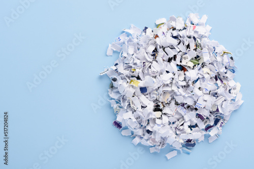 Fotografie Heap of cross cut shredded paper documents on blue background top view with copy