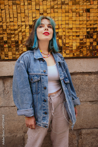 Hippie young woman with blue hair wearing jeans jacket posing outdoors in the street. Good vibes. Street style fashion