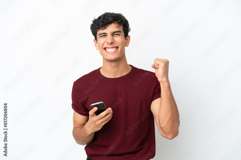 Young Argentinian man isolated on white background with phone in victory position Young Argentinian man isolated on white background with phone in victory position