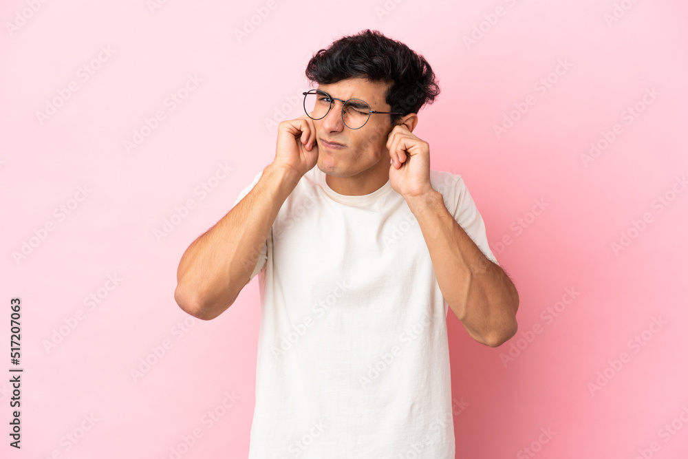 Young Argentinian man isolated on pink background frustrated and covering ears Young Argentinian man isolated on pink background frustrated and covering ears