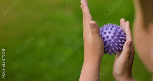 Close-up of a child's hands holding a purple prickly antistress ball. photo
