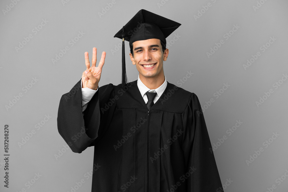 Young Argentinian university graduate isolated on grey background happy and counting three with fingers Young Argentinian university graduate isolated on grey background happy and counting three with fingers