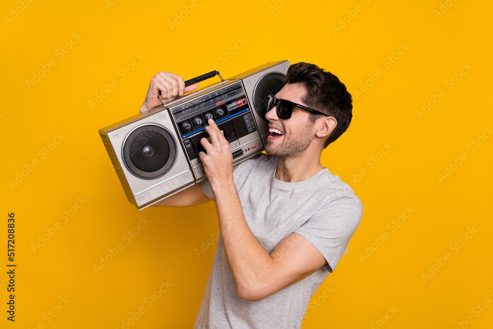 Fototapeta premium Photo of funky brunet millennial guy hold look boombox wear t-shirt glasses isolated on yellow background