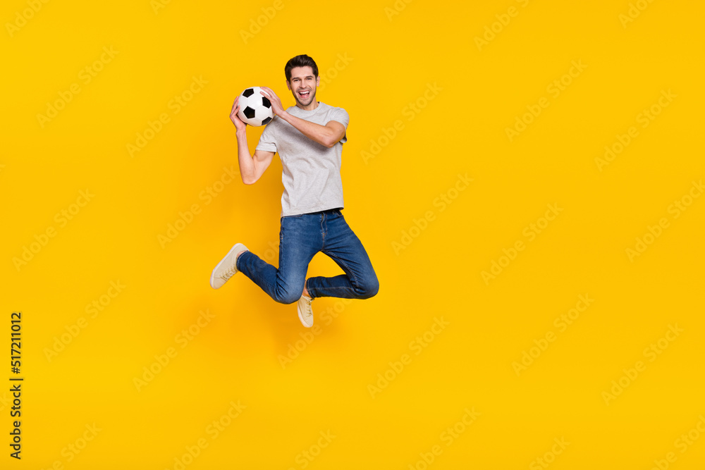 Full length body size view of attractive cheerful guy jumping throwing ball isolated over bright yellow color background