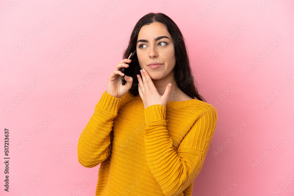 Young caucasian woman using mobile phone isolated on pink background looking up while smiling Young caucasian woman using mobile phone isolated on pink background looking up while smiling