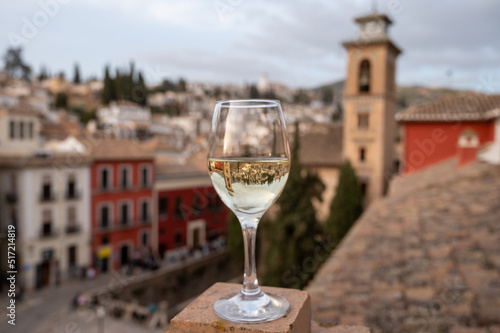 Glass of Spanish dry rueda white wine served on roof terrace with view on old part of Andalusian town Granada, Spain