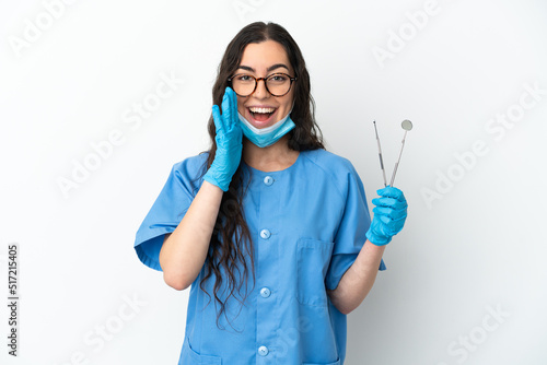 Young woman dentist holding tools isolated on white background shouting with mouth wide open