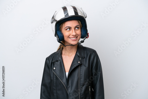 Young caucasian woman with a motorcycle helmet isolated on white background looking to the side and smiling