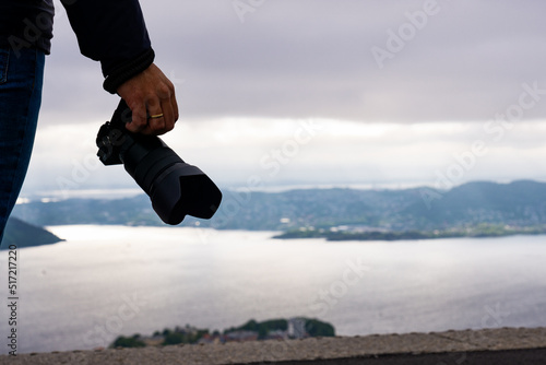 Unrecognizable tourist man with camera in hand and in the background the city of Bergen and the fjord in Norway.