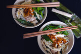 Top view of two bowls of traditional Vietnamese Banh uot long ga with chopsticks