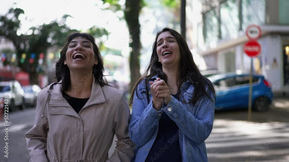 Female friends laughing and smiling while while walking in city sidewalk. Authentic real expression laugh and smile Female friends laughing and smiling while while walking in city sidewalk. Authentic real expression laugh and smile