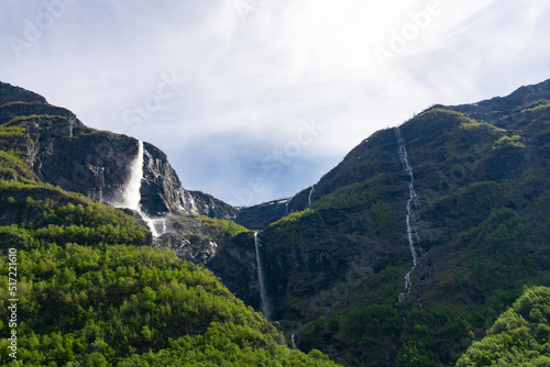 Large waterfall that rises in the mountains surrounded by green trees in Norway.