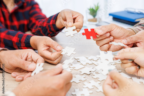 Close up Businesspeople hand holding jigsaw and jigsaw puzzle on the table, success and strategy concept.