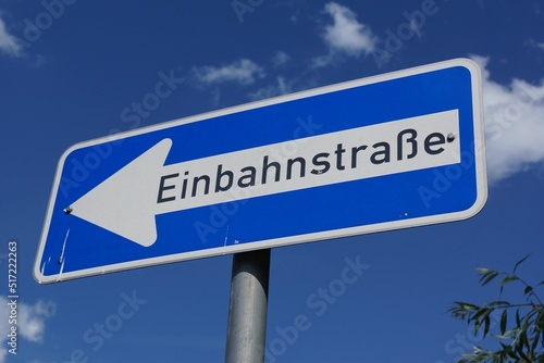 A one-way street sign against a blue sky in Germany