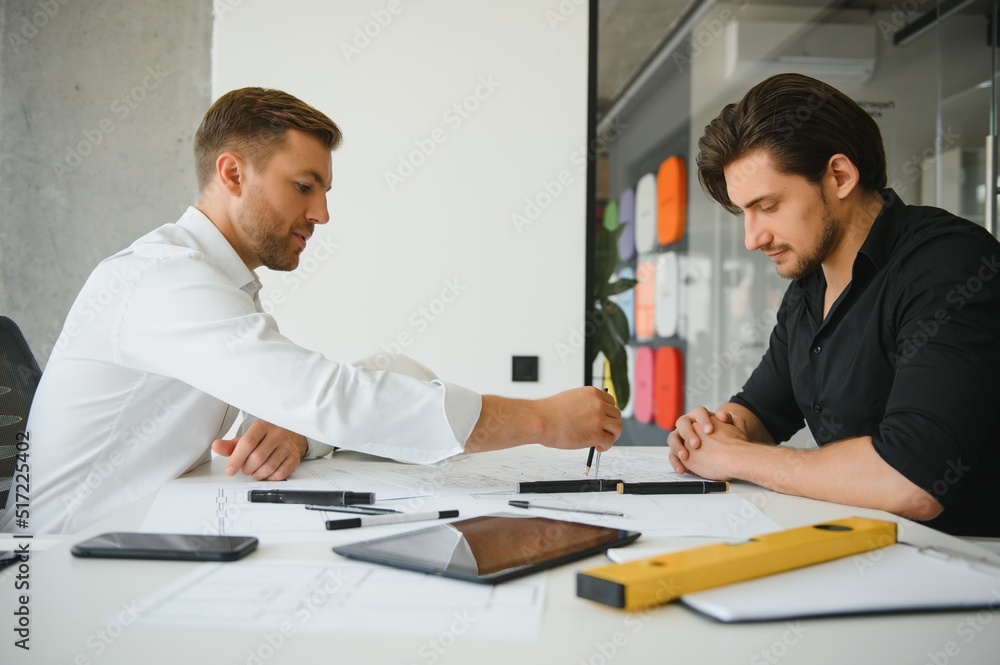 Two engineering working together and using digital tablet looking blueprint and analysis with architectural plan on desk Two engineering working together and using digital tablet looking blueprint and analysis with architectural plan on desk