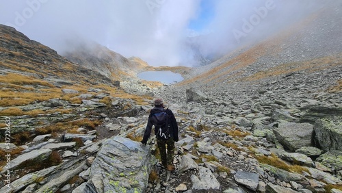 Scenic view of a person hiking on rocks against a lake on a foggy day photo