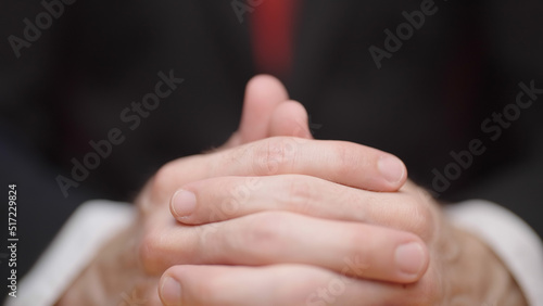 Male person fingers crossed together on table
