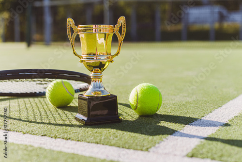 Golden champion cup with tennis racket and balls on the playing court. Sport award. Victory concept © vladdeep