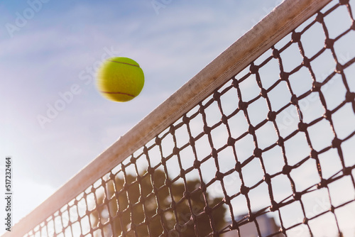 Tennis ball flies close over net, dangerous hit, ball is in motion, view from below.