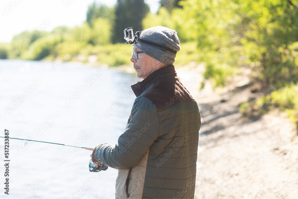 A man fishing with a fishing rod on the river in summer. A man fishing with a fishing rod on the river in summer.