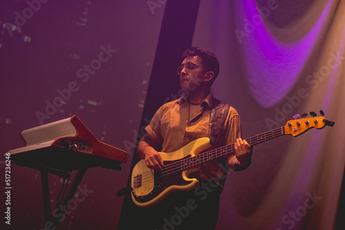 Принти на полотні Young latino bassist and keyboardist with shirt and glasses, and cream bass and