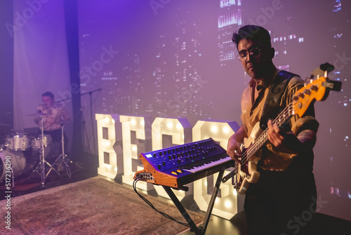 Картината върху платно Young latino bassist and keyboardist with shirt and glasses, and cream bass and