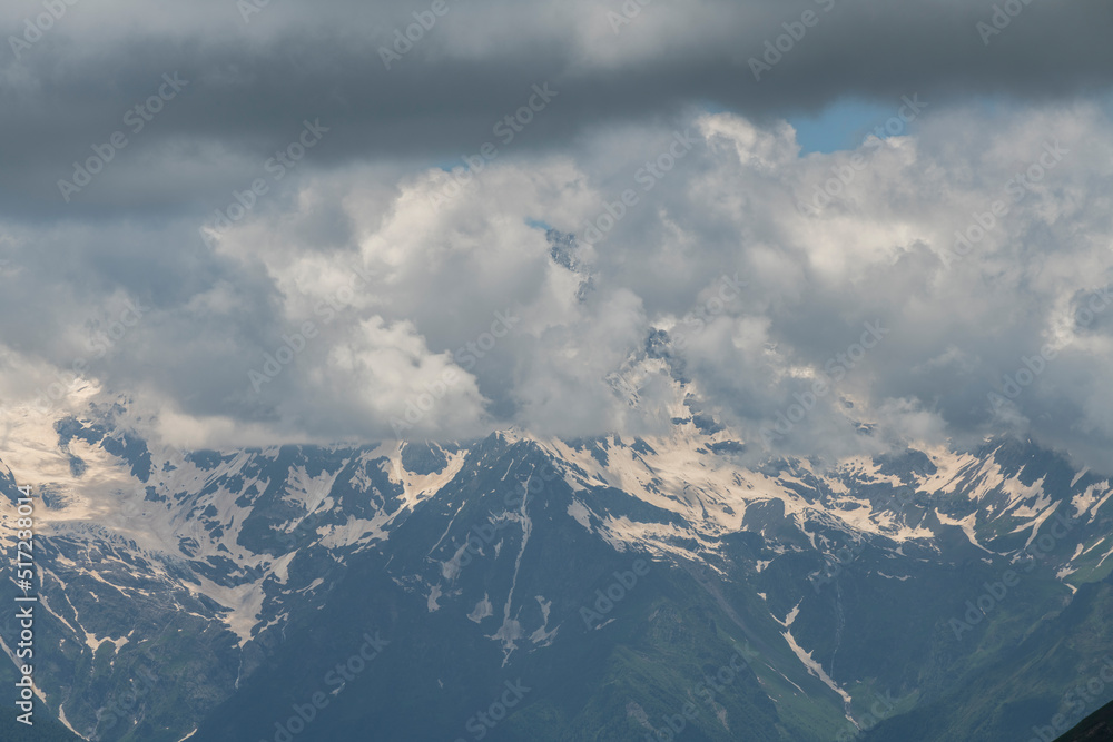 Clouds over the snow covered mountains. High mountains peak, winter landscape.