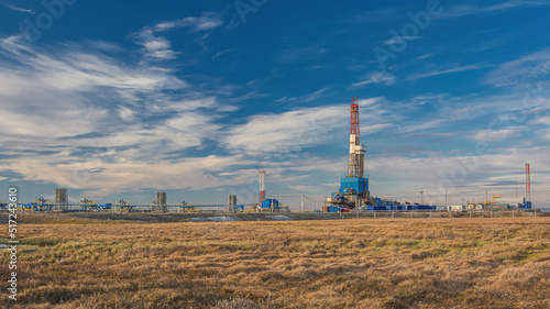 The spring landscape of the Arctic tundra against the background of infrastructure for drilling wells and oil and gas production. In the foreground is a marshy surface after the snow melts