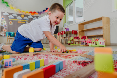 Toddler boy playing with wooden train in kindergarten photo
