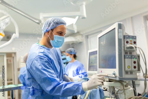 Medical ventilator being monitored by anaesthetist. surgeon using monitor in operating room.