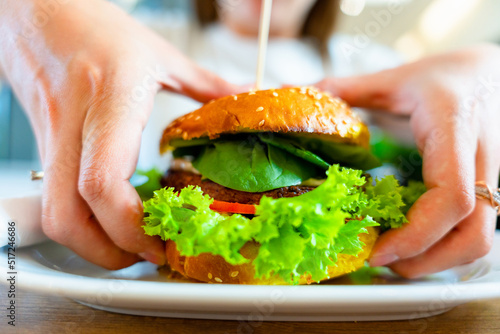 Hamburger vegan healthy vegetarian burger. Salad, avocado, vegetable on veggie sandwich eating cute woman. Tasty vegetarian healthy green food.