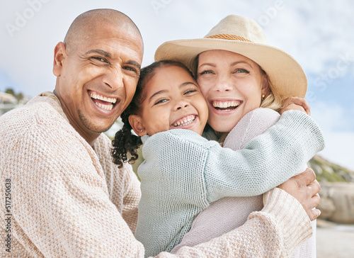 Portrait of happy interracial family on vacation in summer. Smiling and laughing parents bonding with their daughter outside and having fun on the beach. Cute little girl embracing her mom in a hug