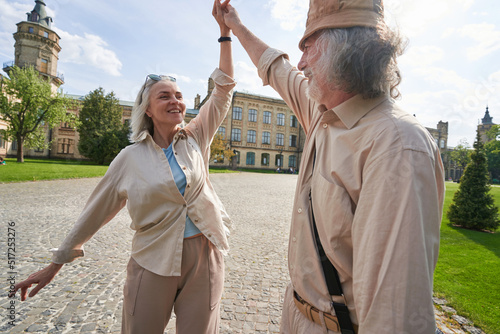 Smiling mature woman dancing with man outdoors in the city