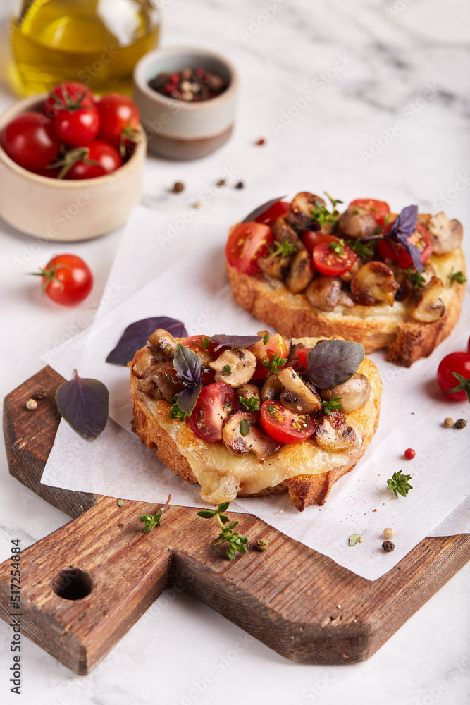 Bruschetta with ciabatta bread, mozzarella cheese, champignon mushrooms and cherry tomatoes. Delicious homemade appetizer. 