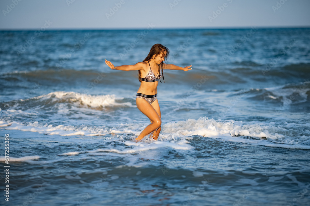 A girl with loose hair walks on the sea with waves and enjoys the sun A girl with loose hair walks on the sea with waves and enjoys the sun