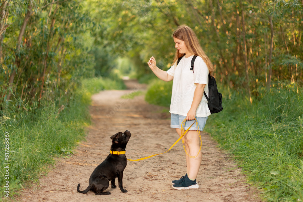 Smiling teenage girl and black dog on dirt road