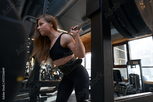 Woman performing barbell exercise in fitness club