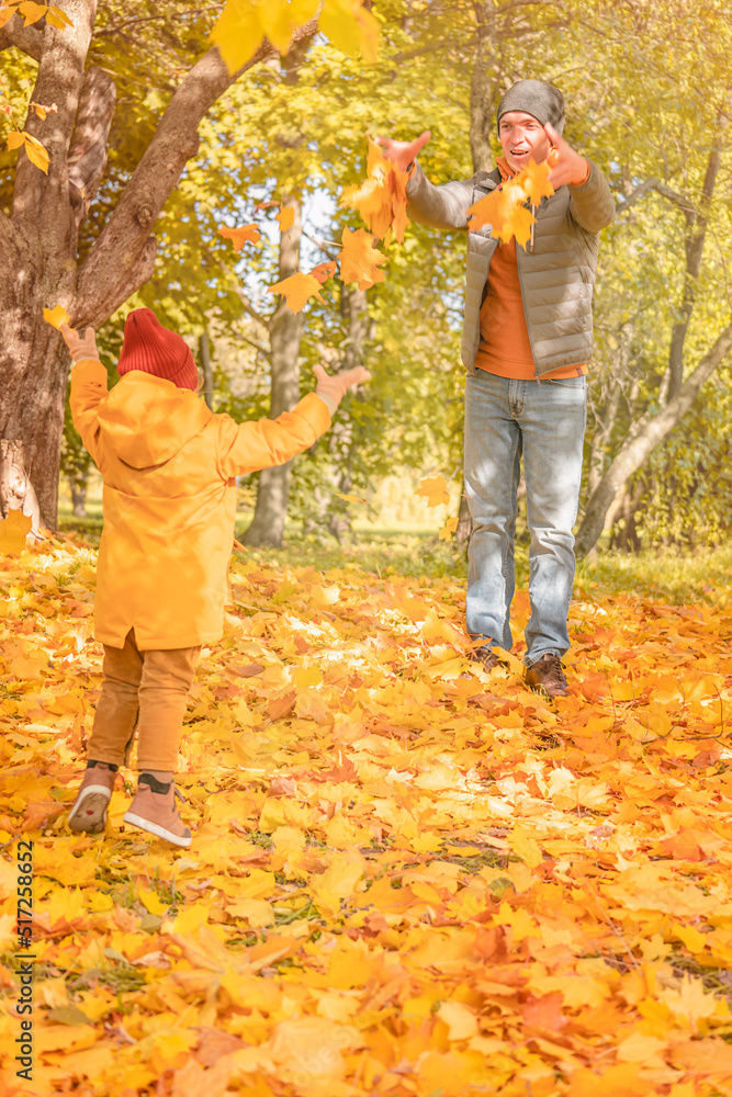 Happy father and child daughter playing with maple leaves on a walk in the autumn park. Happy father and daughter having fun in autumn park Happy father and child daughter playing with maple leaves on a walk in the autumn park. Happy father and daughter having fun in autumn park