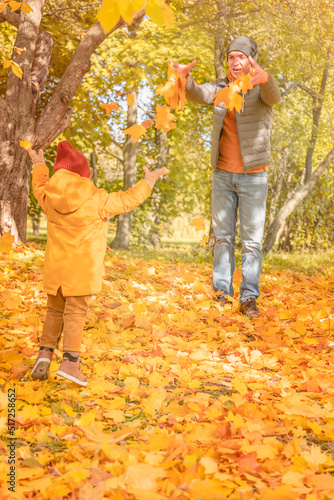 Happy father and child daughter playing with maple leaves on a walk in the autumn park. Happy father and daughter having fun in autumn park
