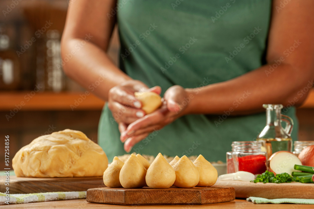 Woman hands preparing brazilian croquette (coxinha de frango) on a wooden table. Woman hands preparing brazilian croquette (coxinha de frango) on a wooden table.
