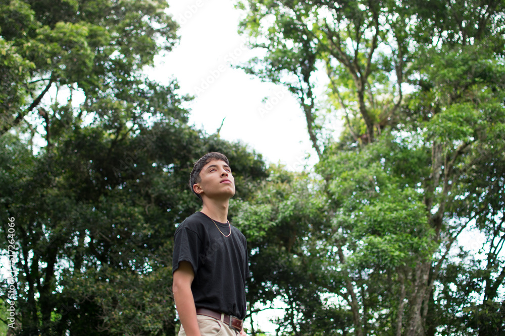 Young man standing in the park watches the sky in a summer day Young man standing in the park watches the sky in a summer day