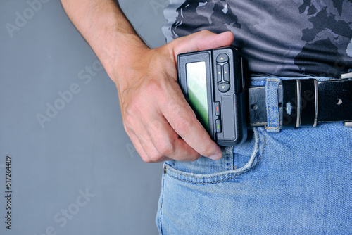 Hand holds pager weighing on belt jeans. photo