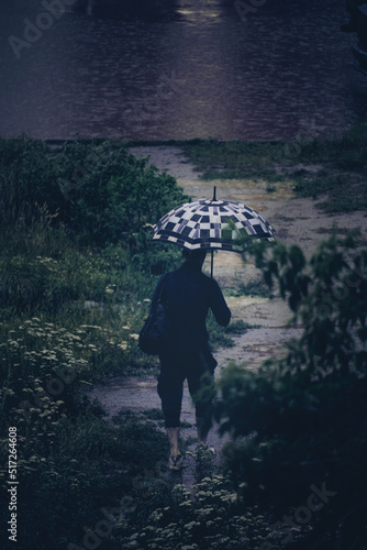 Man with umbrella walking rain wet path.