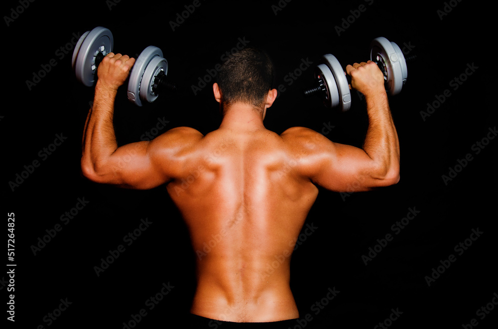 Young attractive sportsman with dumbbells. Male athletic body.